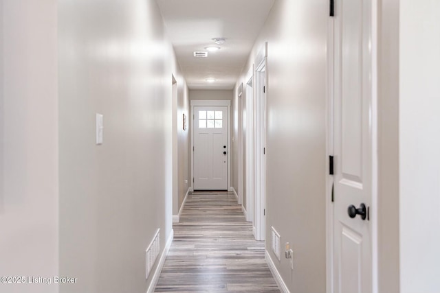 corridor with wood finished floors, visible vents, and baseboards