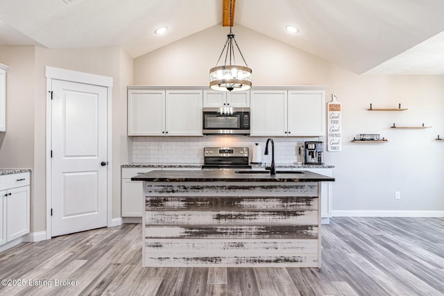 kitchen with light wood finished floors, appliances with stainless steel finishes, backsplash, and a sink