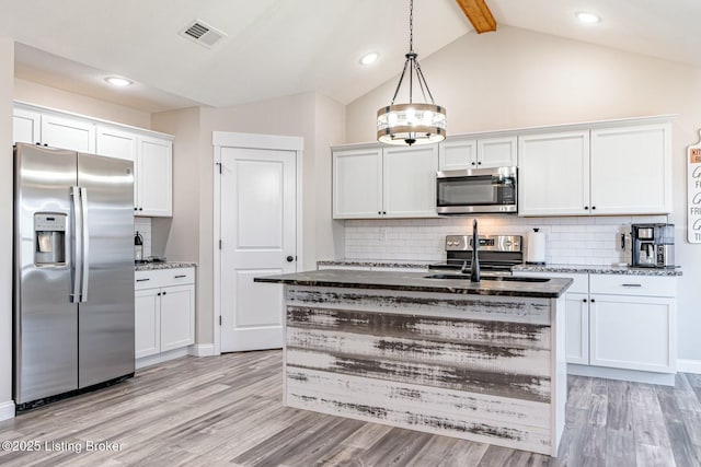 kitchen with stainless steel appliances, light wood-style flooring, white cabinetry, a sink, and dark stone counters