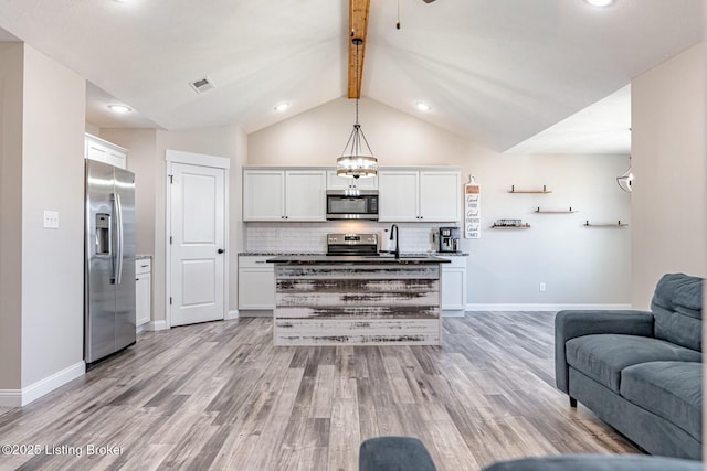 kitchen featuring white cabinetry, light wood-style floors, open floor plan, appliances with stainless steel finishes, and tasteful backsplash