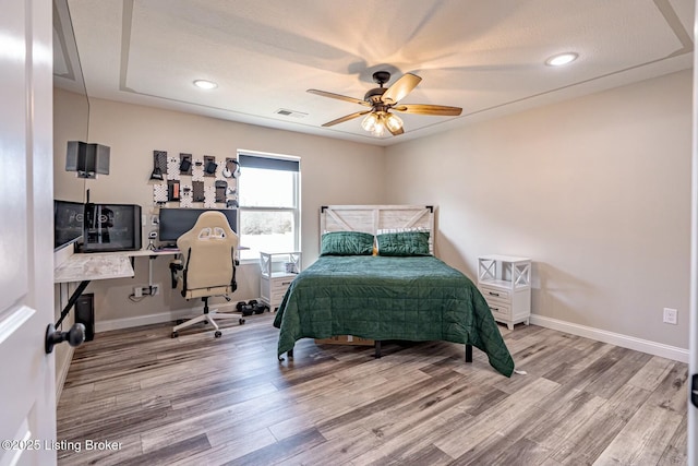 bedroom with ceiling fan, wood finished floors, visible vents, and baseboards