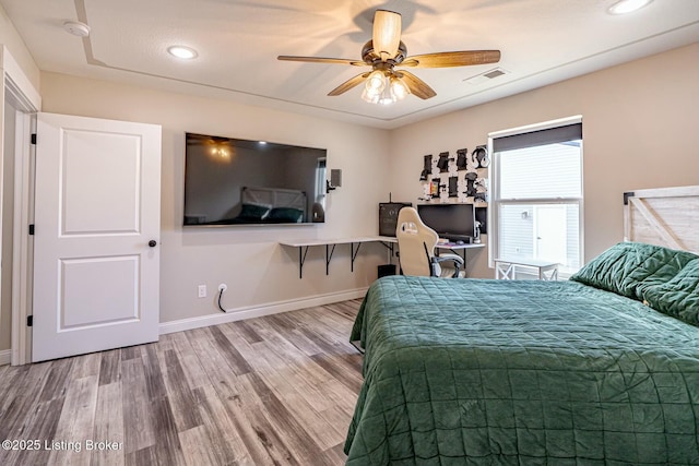 bedroom featuring ceiling fan, wood finished floors, visible vents, and baseboards