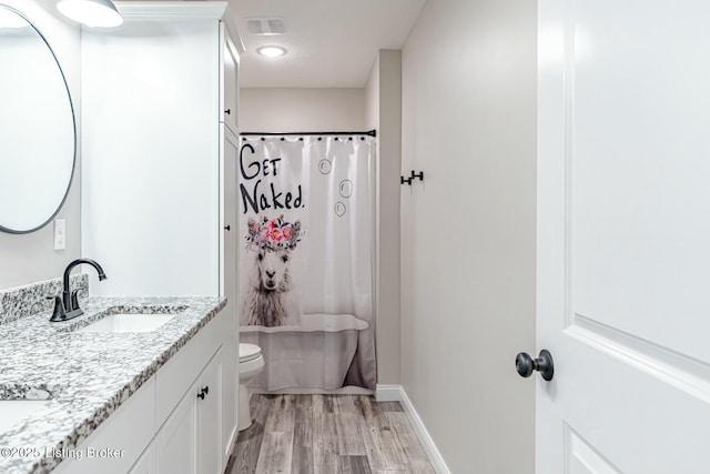 bathroom featuring curtained shower, toilet, wood finished floors, vanity, and baseboards