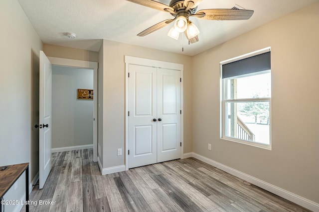 unfurnished bedroom with ceiling fan, a closet, wood finished floors, and baseboards