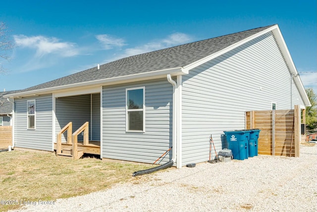 back of property with a shingled roof and a yard