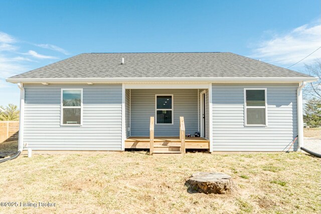 rear view of property with covered porch, roof with shingles, and a yard