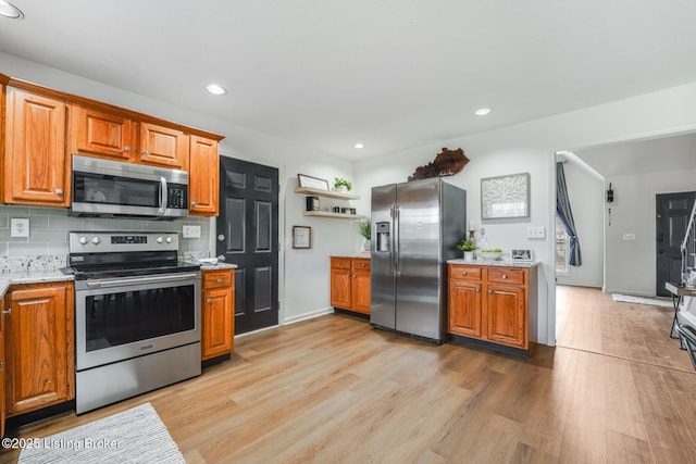 kitchen featuring light wood-style flooring, appliances with stainless steel finishes, backsplash, open shelves, and brown cabinetry