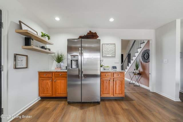 kitchen with dark wood-style floors, brown cabinetry, stainless steel refrigerator with ice dispenser, and open shelves