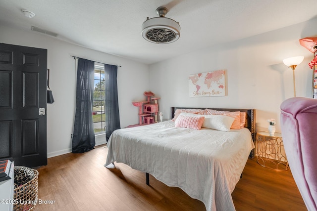 bedroom with baseboards, visible vents, ceiling fan, and wood finished floors