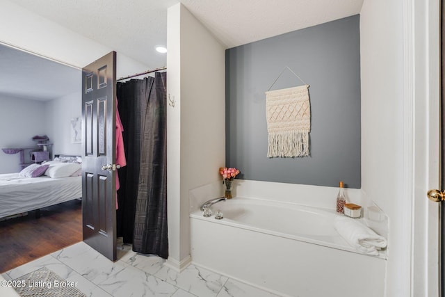 ensuite bathroom with ensuite bathroom, a textured ceiling, a garden tub, a shower with shower curtain, and marble finish floor