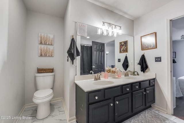 full bathroom featuring toilet, marble finish floor, baseboards, and a sink