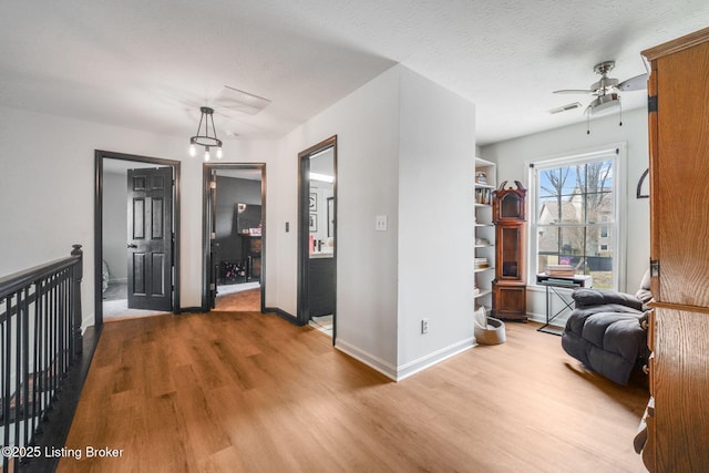 interior space with light wood-type flooring, visible vents, a textured ceiling, and baseboards