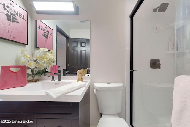 bathroom featuring a shower stall, toilet, and vanity