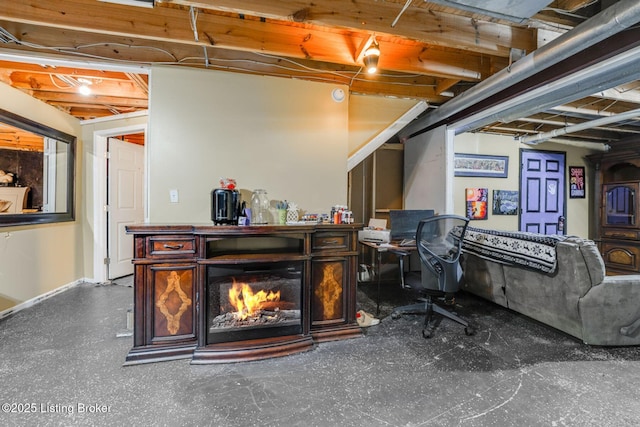 unfinished basement with a lit fireplace and baseboards