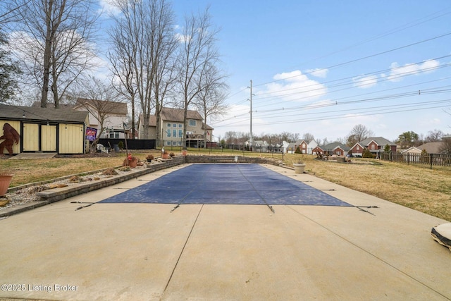 view of swimming pool featuring a residential view, fence, a patio, and a yard