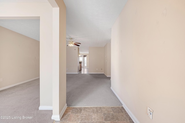 hallway featuring baseboards, arched walkways, and light colored carpet