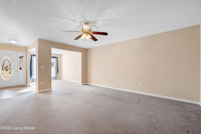 empty room with light colored carpet, a textured ceiling, and baseboards