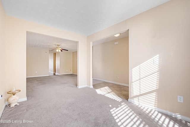 unfurnished room with a ceiling fan, baseboards, a textured ceiling, and carpet flooring