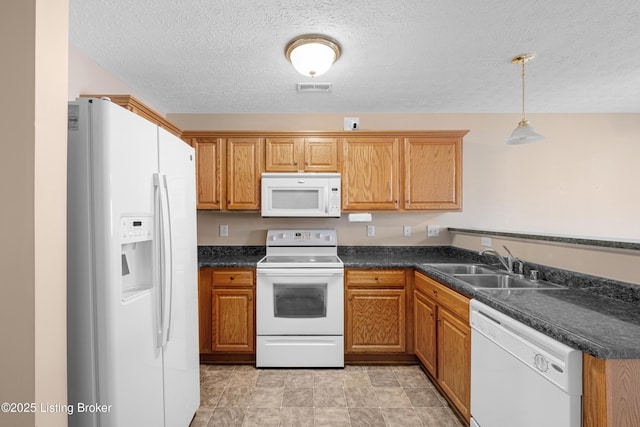 kitchen with dark countertops, white appliances, visible vents, and a sink