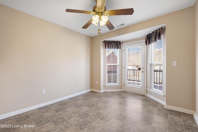 unfurnished room with a ceiling fan, visible vents, and baseboards