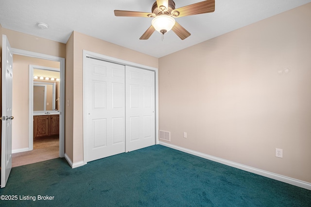 unfurnished bedroom featuring baseboards, visible vents, ceiling fan, dark colored carpet, and a closet