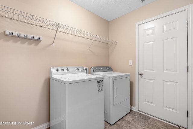 laundry room featuring a textured ceiling, laundry area, washer and clothes dryer, and baseboards