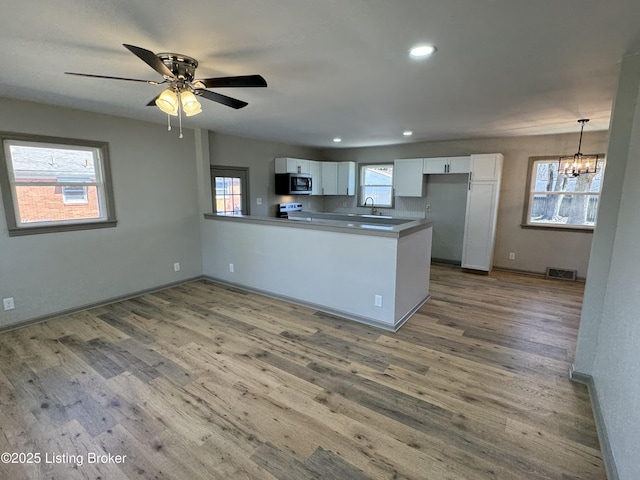 kitchen with stainless steel appliances, visible vents, white cabinets, and a peninsula