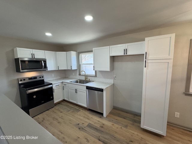 kitchen with stainless steel appliances, light countertops, white cabinets, and a sink