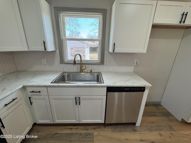 kitchen with a sink, white cabinetry, light stone counters, and dishwasher