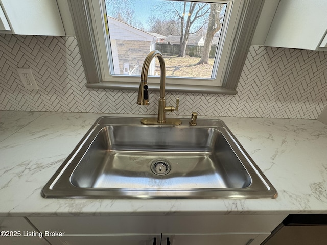 interior details with backsplash, light countertops, and a sink