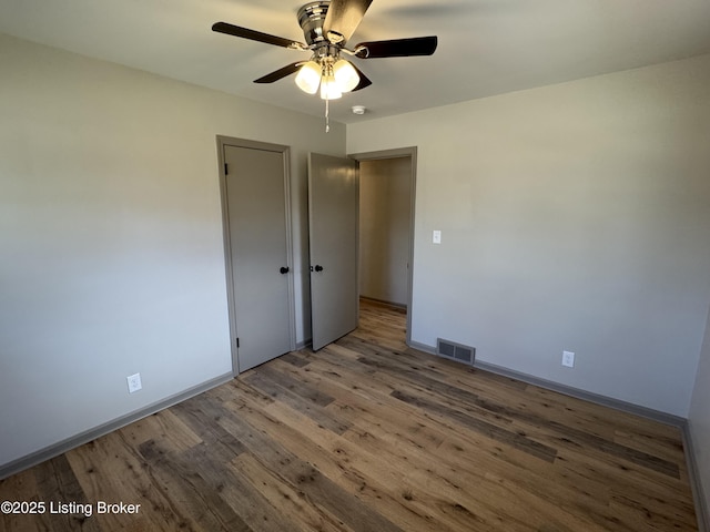 unfurnished bedroom with a ceiling fan, wood finished floors, visible vents, and baseboards