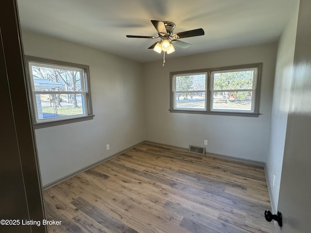 spare room with a healthy amount of sunlight, light wood-style floors, baseboards, and visible vents