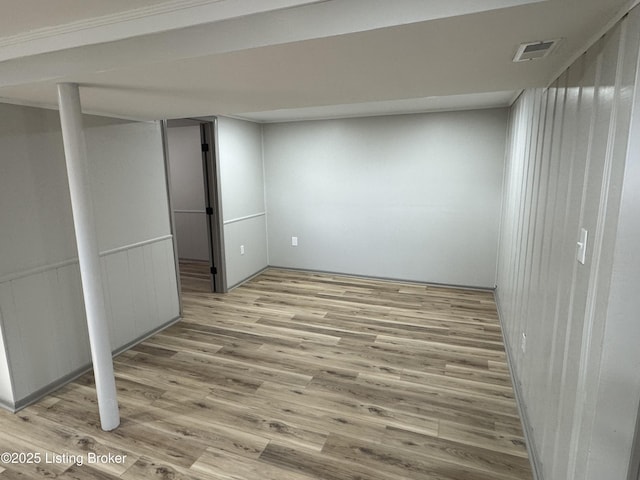 finished basement featuring wainscoting, wood finished floors, and visible vents