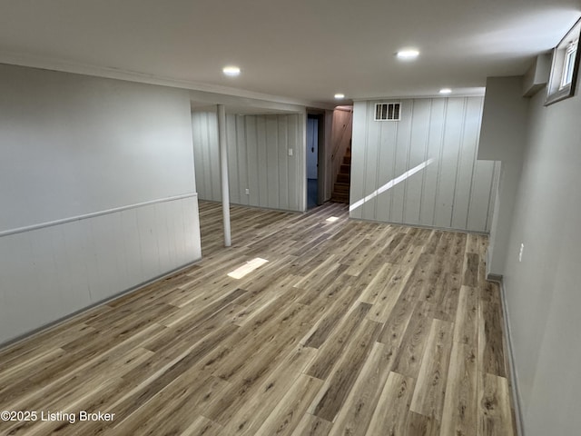 finished basement with recessed lighting, wood finished floors, visible vents, and stairs