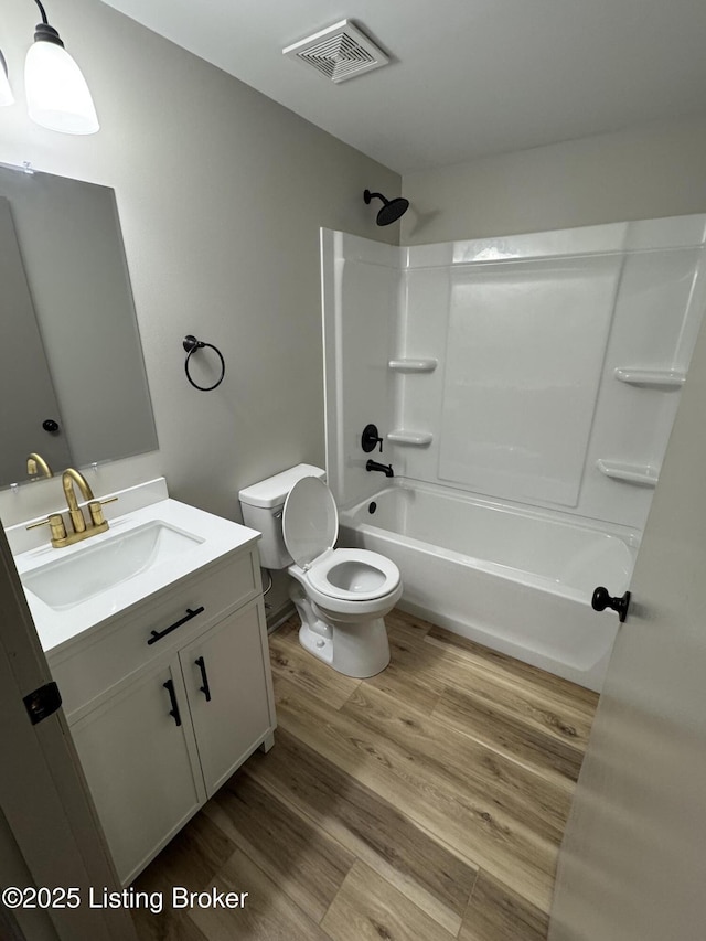 full bathroom featuring bathing tub / shower combination, visible vents, toilet, vanity, and wood finished floors