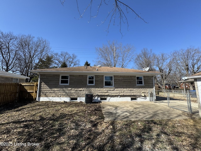 back of property featuring a patio, a gate, fence, cooling unit, and stone siding