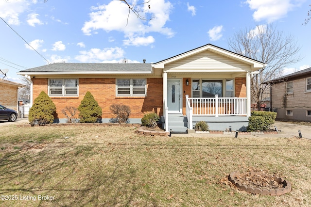 view of front of property with a shingled roof, covered porch, brick siding, and a front lawn