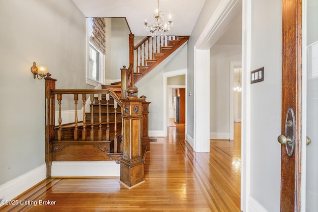 stairs featuring a chandelier, baseboards, and wood finished floors