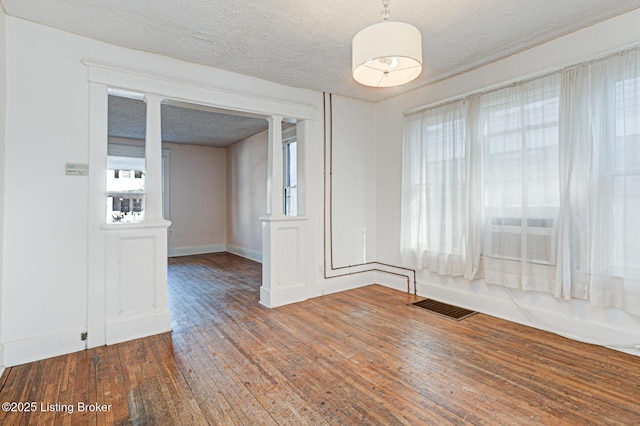 interior space with wood-type flooring, visible vents, a textured ceiling, and baseboards