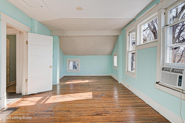 bonus room with a textured ceiling, dark wood-style flooring, visible vents, baseboards, and vaulted ceiling