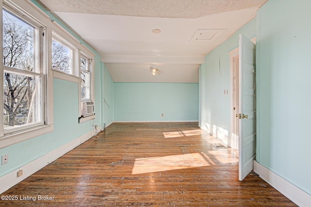 spare room with lofted ceiling, cooling unit, dark wood finished floors, and a textured ceiling