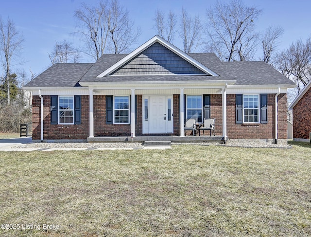 view of front of home featuring brick siding, a shingled roof, covered porch, and a front yard