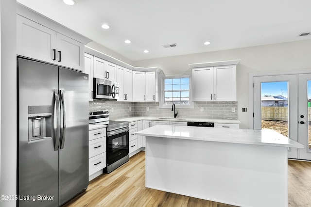 kitchen with a center island, light countertops, visible vents, appliances with stainless steel finishes, and white cabinetry