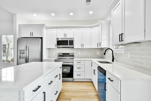 kitchen with stainless steel appliances, a sink, visible vents, white cabinets, and light stone countertops