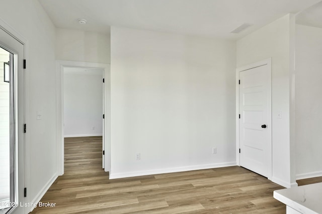 unfurnished room with light wood finished floors, visible vents, and baseboards