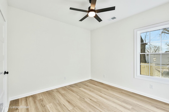 empty room featuring a healthy amount of sunlight, light wood-type flooring, visible vents, and baseboards