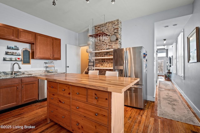 kitchen with a center island, dark wood-type flooring, a sink, wood counters, and stainless steel fridge