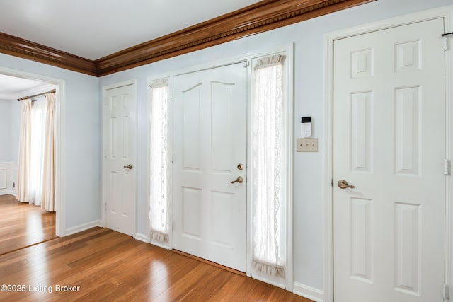 foyer featuring light wood-style floors, baseboards, and ornamental molding