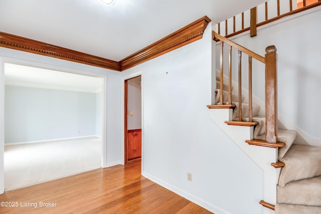 stairs featuring baseboards, wainscoting, wood finished floors, and crown molding