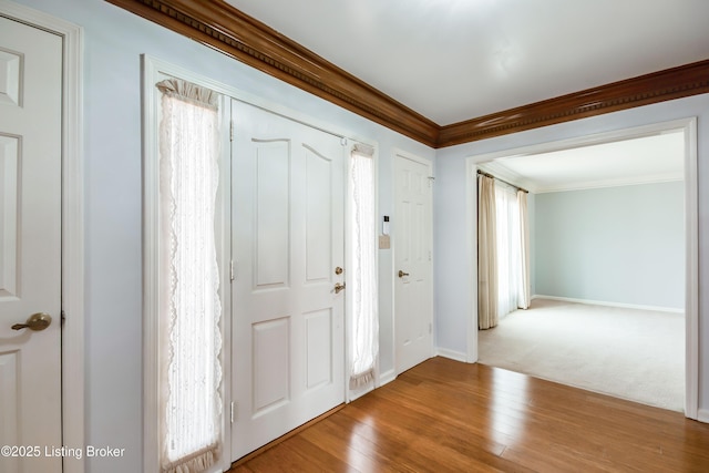 foyer featuring ornamental molding, baseboards, and wood finished floors